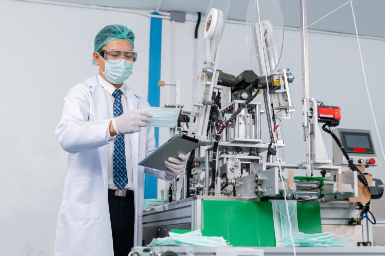 Man worker wear uniform are checking quality medical mask of manufacturer factory.